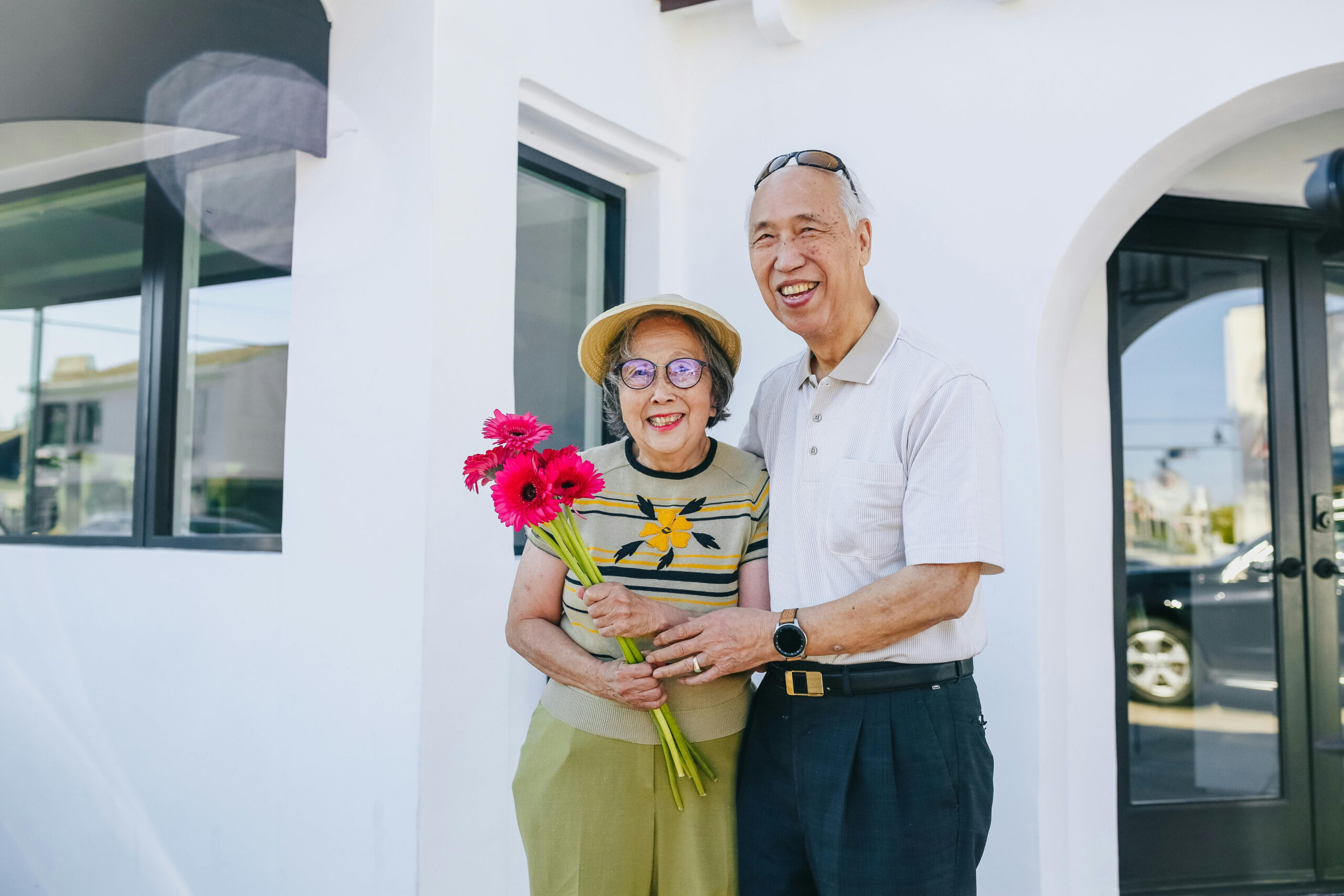 An elderly couple posing for a photo and holding flowers An elderly couple posing for a photo and holding flowers